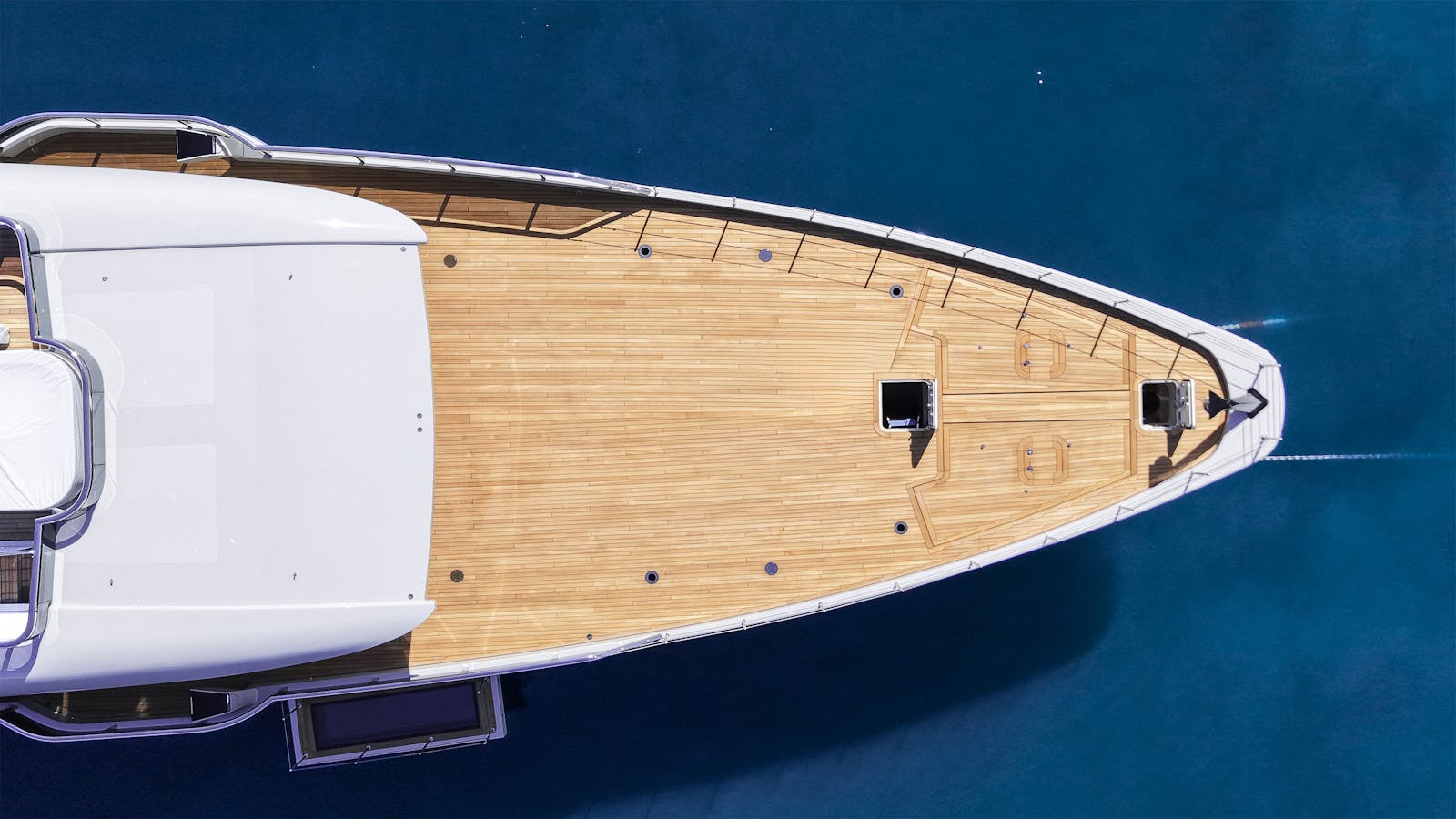 Top-down view of a sleek luxury yacht cruising in the vibrant blue waters of Malta.