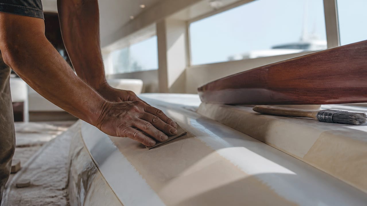 Craftsman hands finishing yacht hull close-up