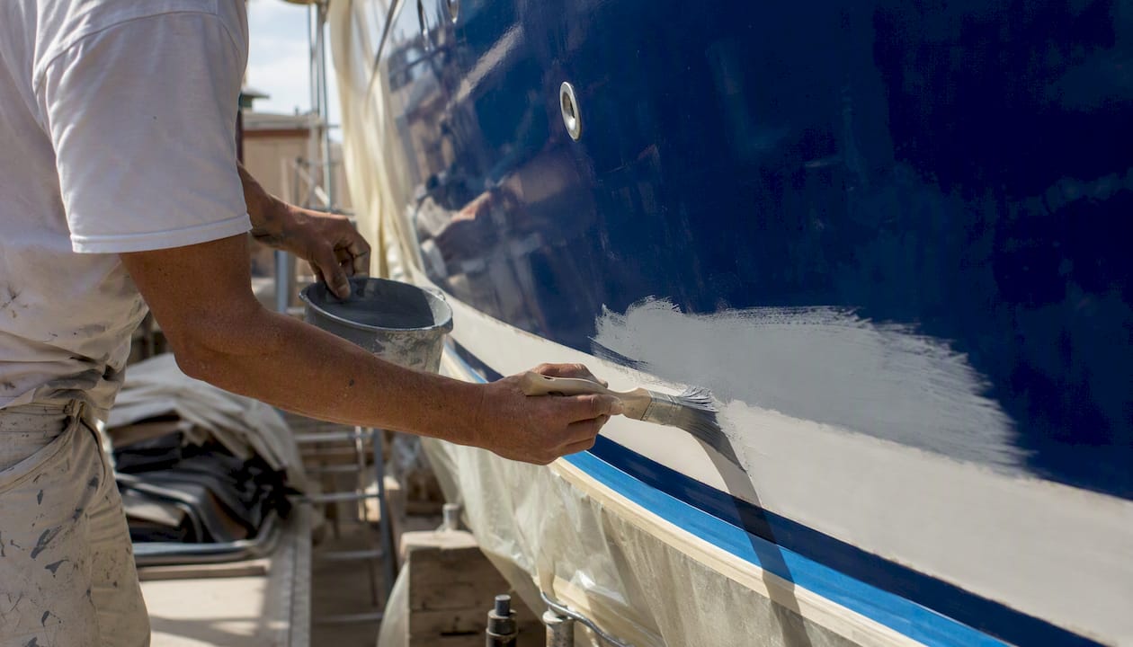 Hands sanding yacht hull in shipyard