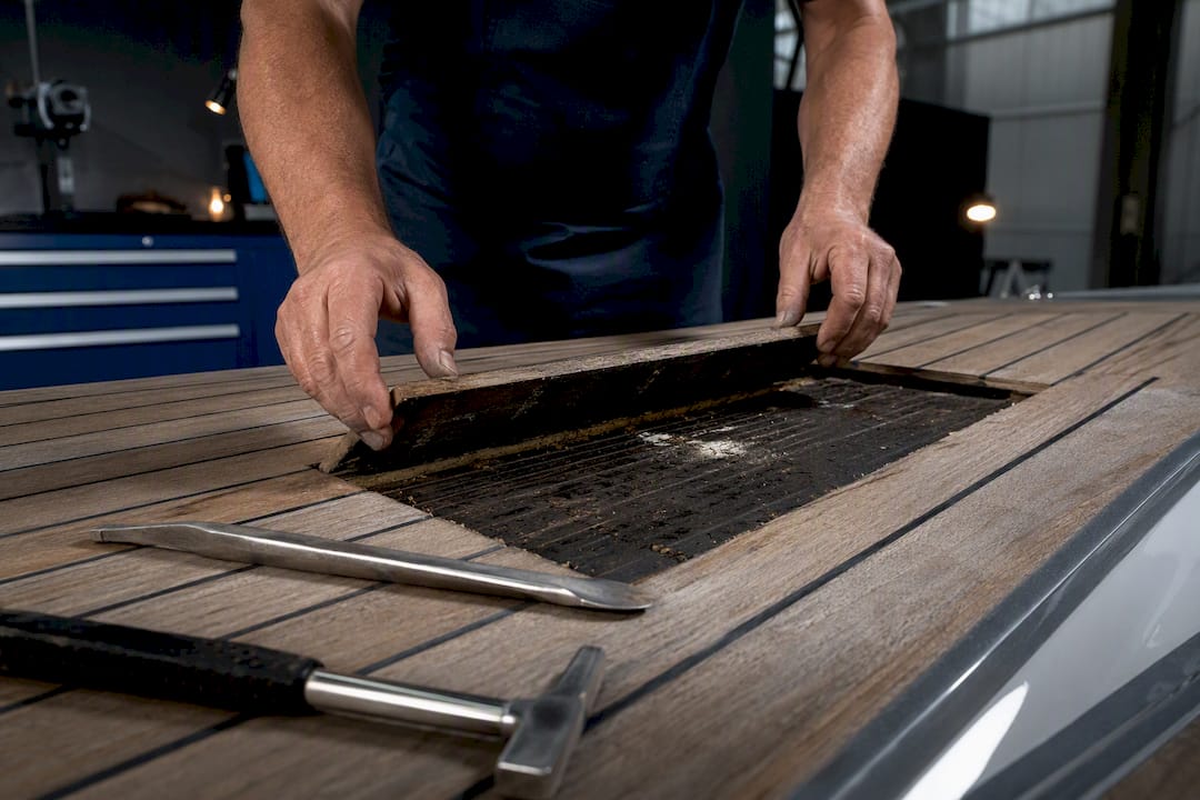 Technician exposing substrate beneath teak deck